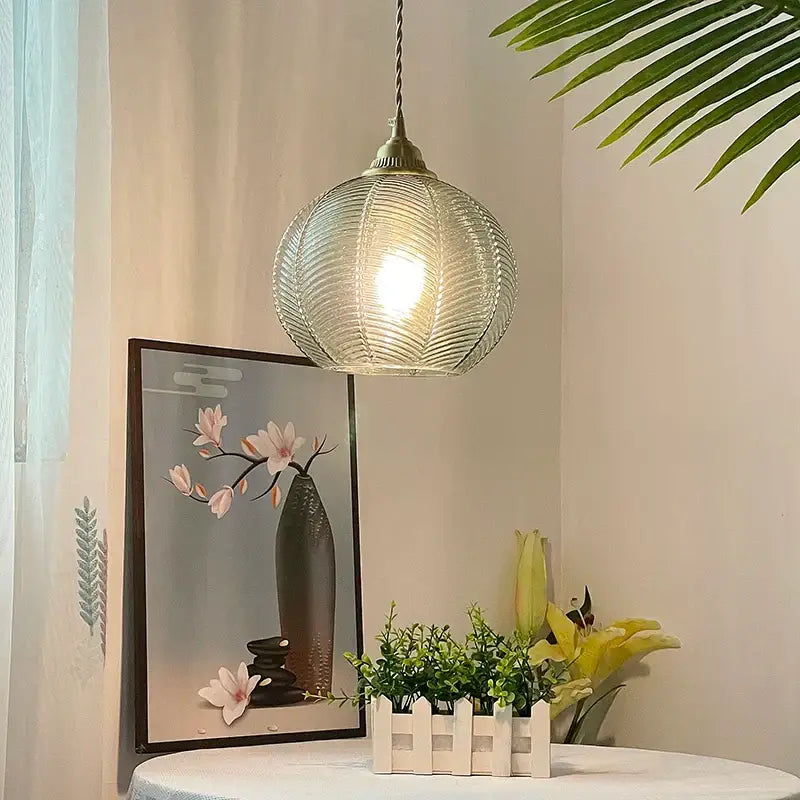 Modern ribbed blue glass led pendant light featuring a spherical design with brass fixture and twisted cord for kitchens
