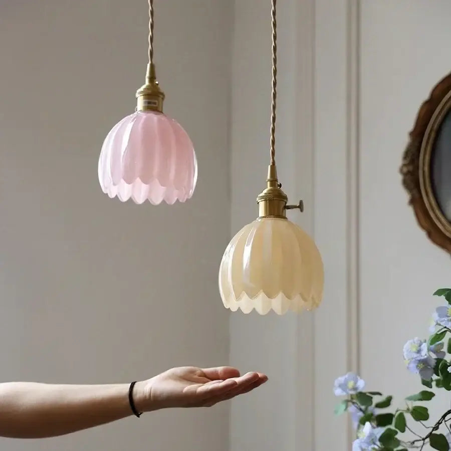 Two petal-shaped pendant lights with frosted glass shades hang from twisted brass cords in elegant decorbites blue glass style