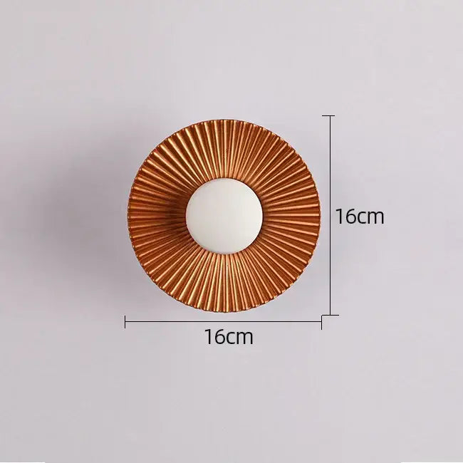 Circular wall-mounted mirror with bronze sunburst metal frame and white glass panel complements modern led wall lamps