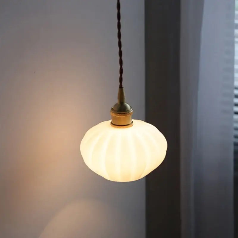 Modern ribbed copper white glass pendant lamp with warm glowing off-white shade and brass fixture for living room decorbites decor