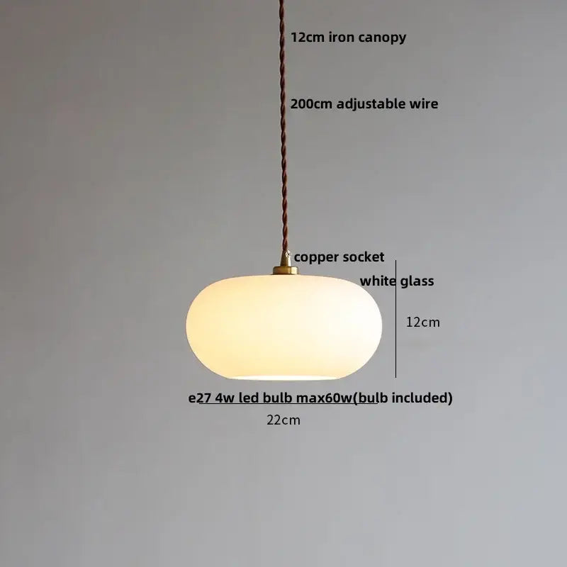 A warm glowing pendant lamp with a smooth white copper white glass shade and copper socket for decorbites copper white decor