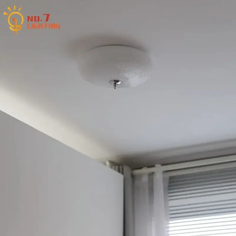 Modern ribbed cream glass round ceiling light fixture with white textured base and chrome mounting screw for bedroom lighting
