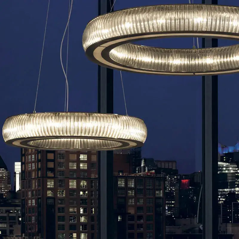 Two illuminated ribbed crystal led ceiling pendant lights hang against a night city skyline for modern decorbites crystal led decor