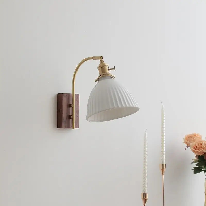 A vintage-style wall sconce with brass arm and off-white ribbed ceramic shade on dark wood backplate for wall lights decorbites ceramic walnut