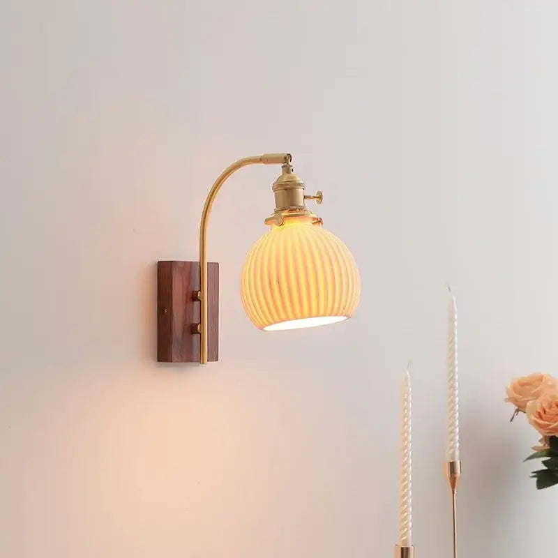 A warm-toned ribbed glass wall light with brass arm and ceramic walnut led wooden backplate for modern decorbites bedroom sconce