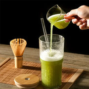 Modern ribbed glass cup with lid and straw filled with vibrant green matcha tea topped with frothy white layer