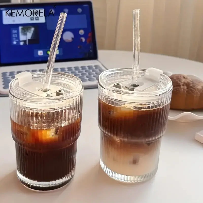 Modern ribbed stripe glass cup with white lid and straw filled with iced coffee made of clear glass cup