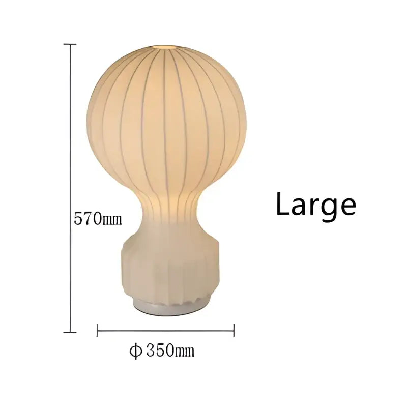 Cream-colored ribbed silk table lamp with ceramic fluted base and metallic silver circular foot for bedroom use