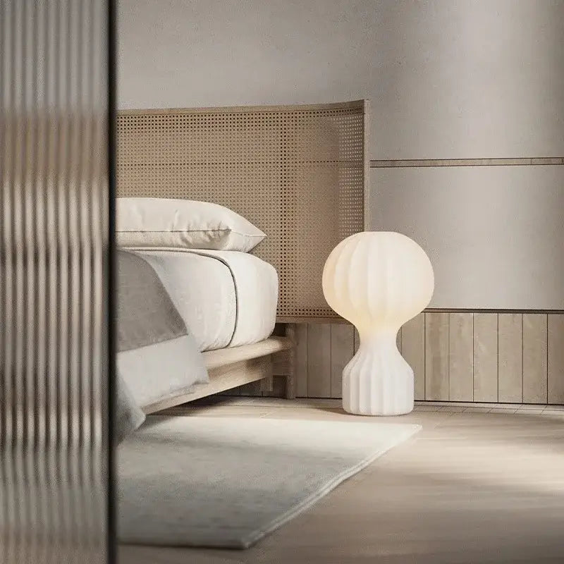 A sleek white ceramic silk table lamp with ribbed spherical shade and fluted base for modern bedroom use