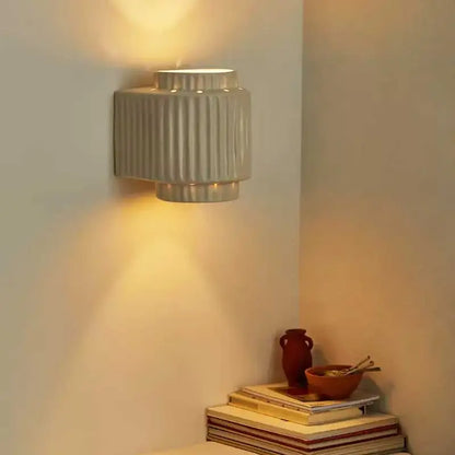 A sleek cream white resin wall lamp with vertical ridges and tiered design for modern bedroom decorbites lighting