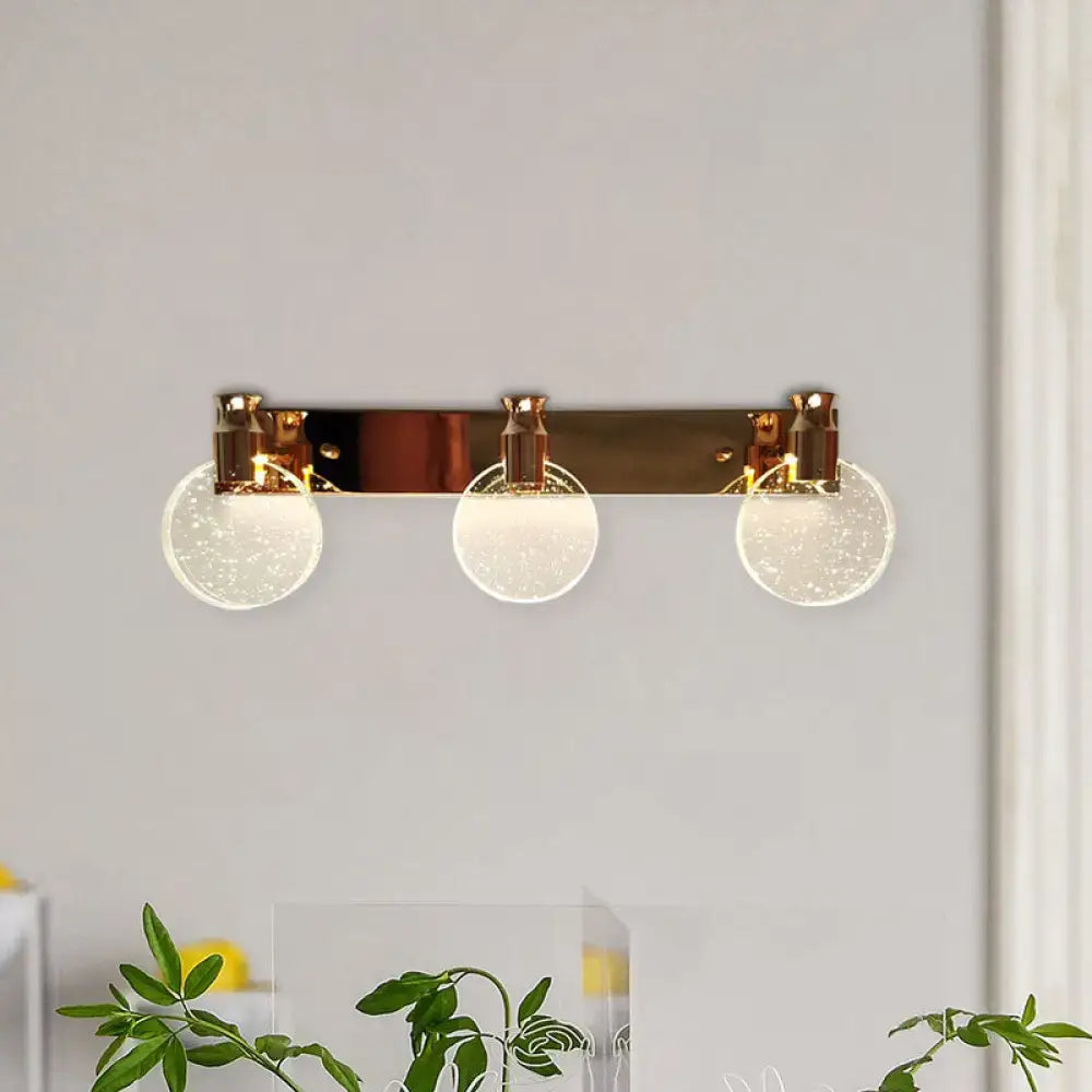 Modern rose gold three-light wall vanity light with frosted glass globe shades and metal frame for bathroom use