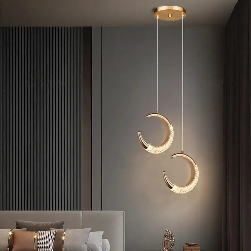 Two elegant gold acrylic led crescent moon pendant lights with crystal accents in a modern acrylic led chandelier fixture