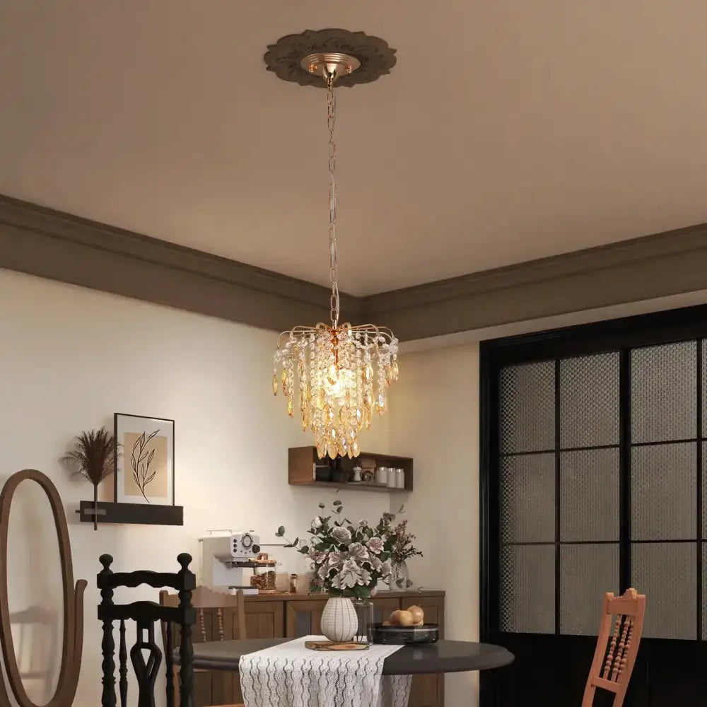 A modern rose gold pendant light with amber crystal led droplets hanging from a decorative ceiling plate