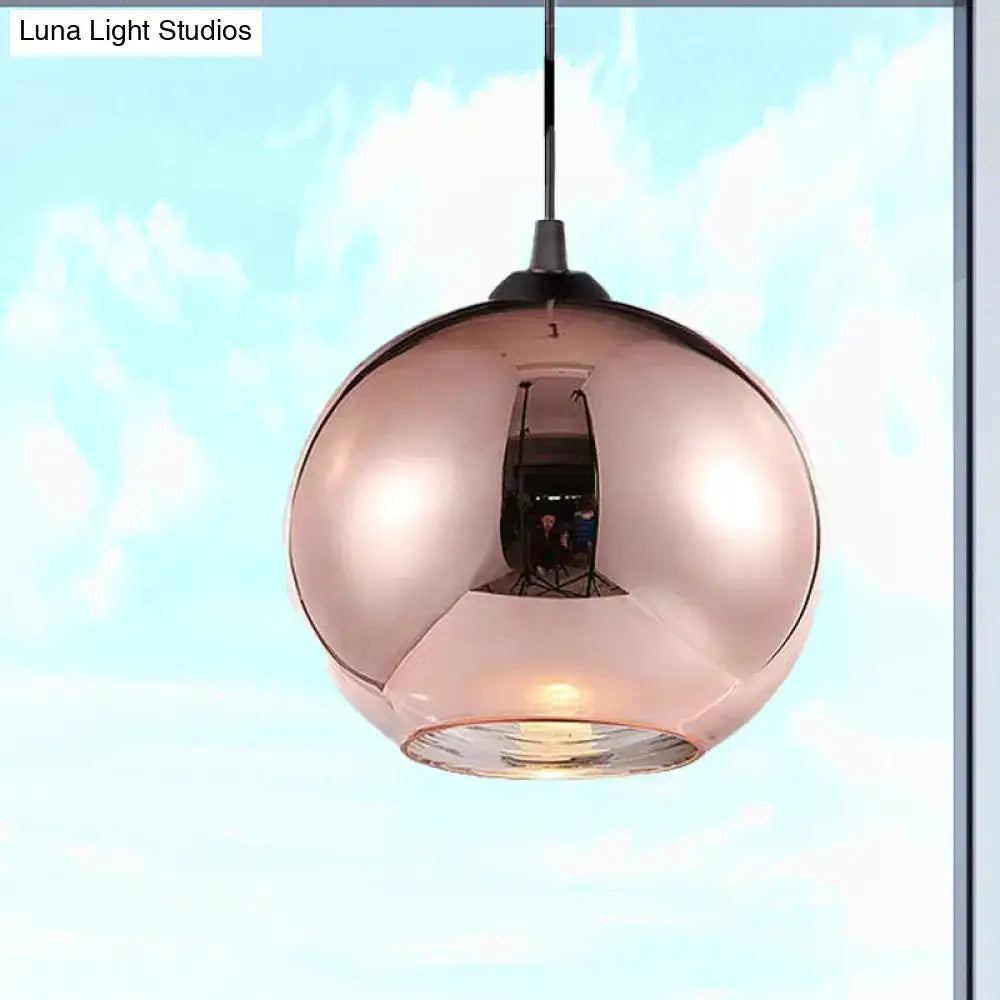 Modern rose gold copper sphere pendant light with a reflective glass globe and black metal hardware for kitchen bar use