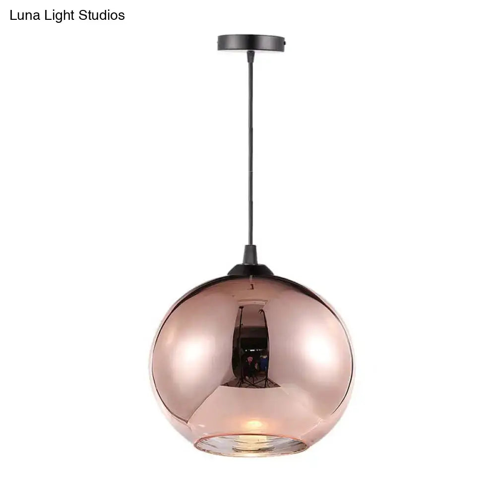 Modern rose gold copper sphere pendant light with a sleek mirrored glass globe and black metal hardware for kitchen bar