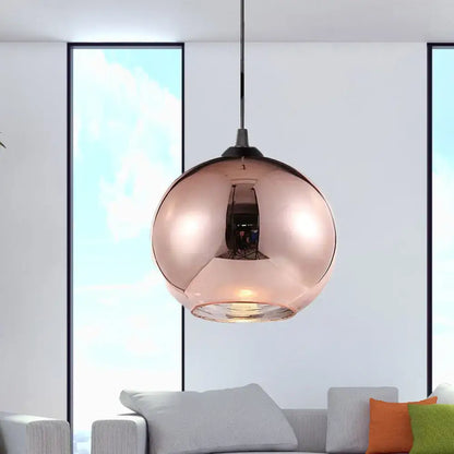 Modern rose gold copper sphere pendant light featuring a sleek reflective glass globe and black metal hardware for kitchen bar