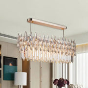A modern rose gold crystal island lamp with a rectangular frame and oval clear cascading crystal teardrop pendants