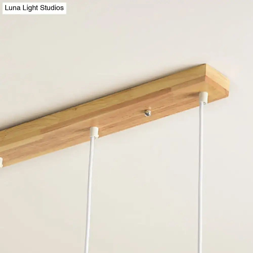 Lightweight wooden bar pendant light with natural finish and white cords complementing modern rose gold drum island chandelier