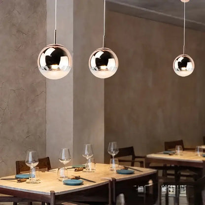 Modern rose gold and frosted glass ball pendant lights by decorbites with polished chrome finish above dining table