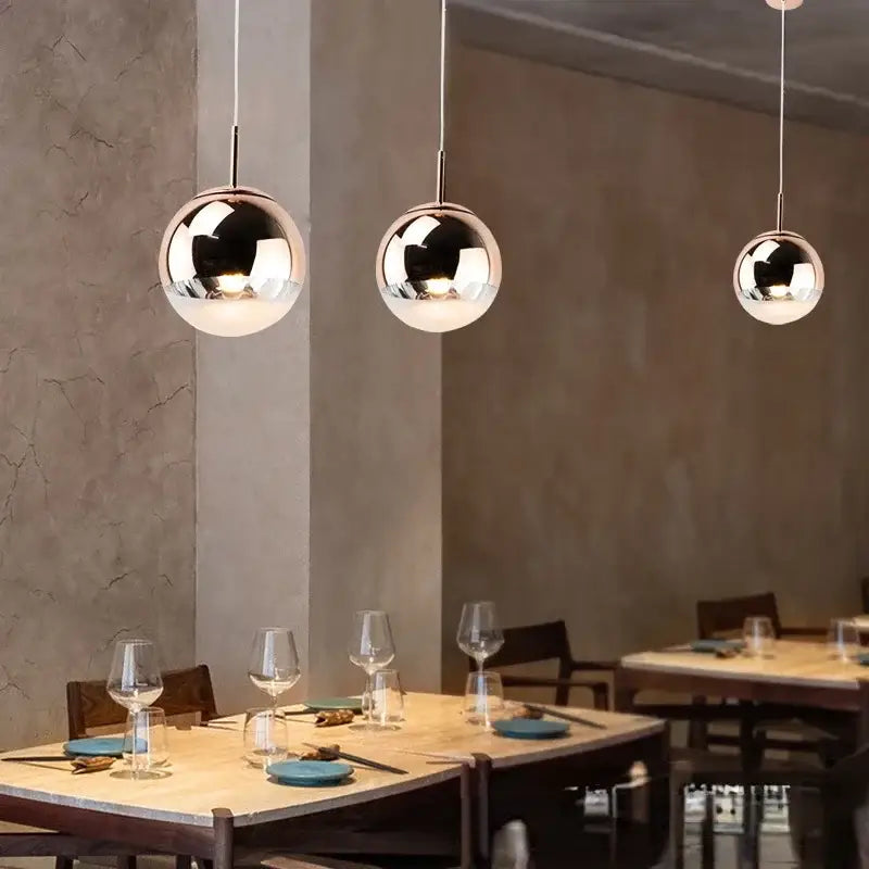 Modern rose gold and frosted glass ball pendant lights by decorbites with polished chrome finish above dining table