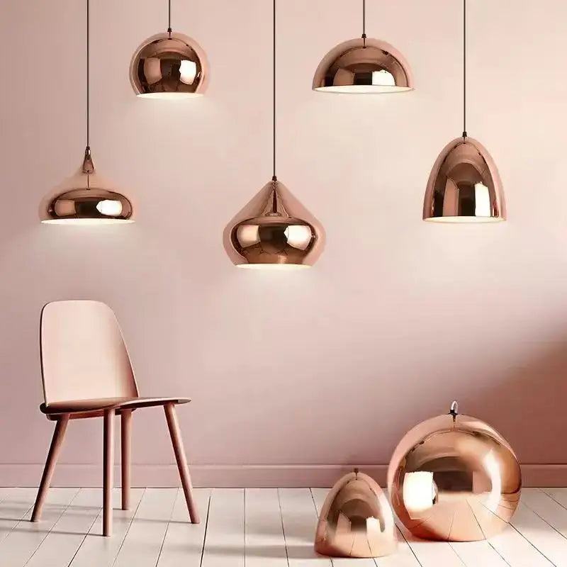 A set of sleek rose gold pendant lights with reflective metallic finishes and varying dome shapes for decorbites rose gold decor