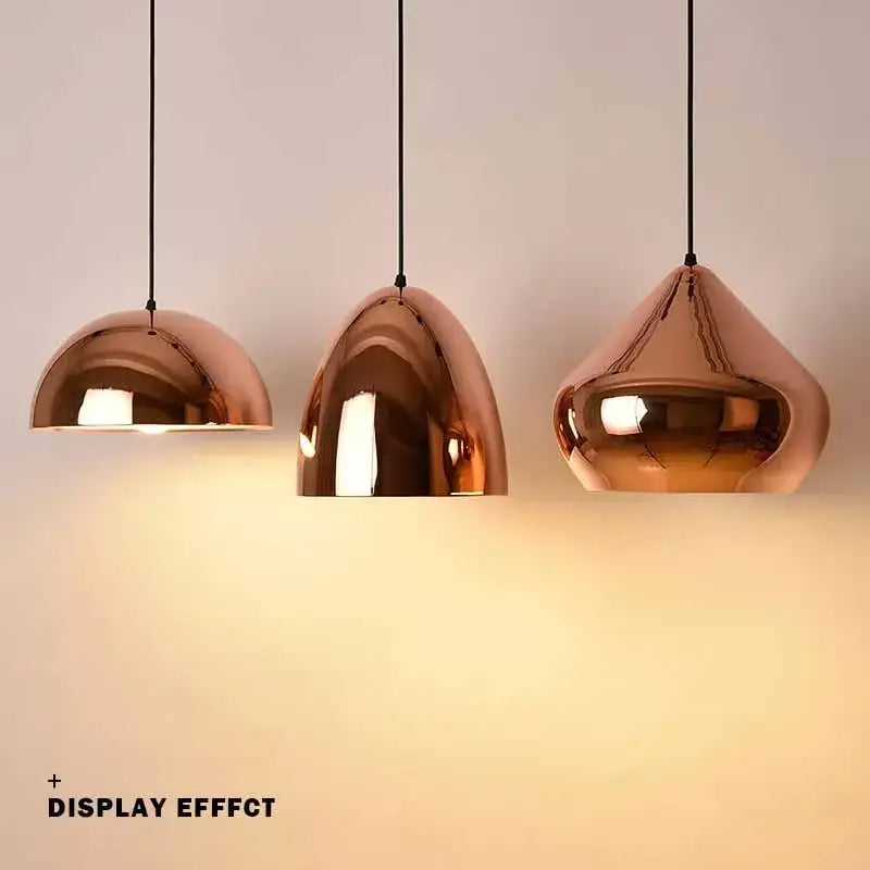 Three copper finished rose gold pendant lights with dome-shaped shades hang from black cords for dining room decorbites decor