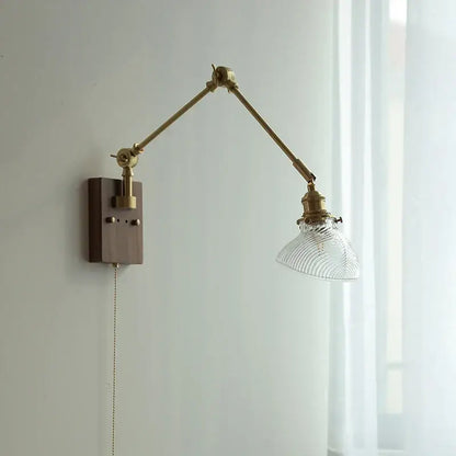 Adjustable modern rotatable brass wall light fixture with clear ribbed glass shade and dark wood mounting plate for stairs