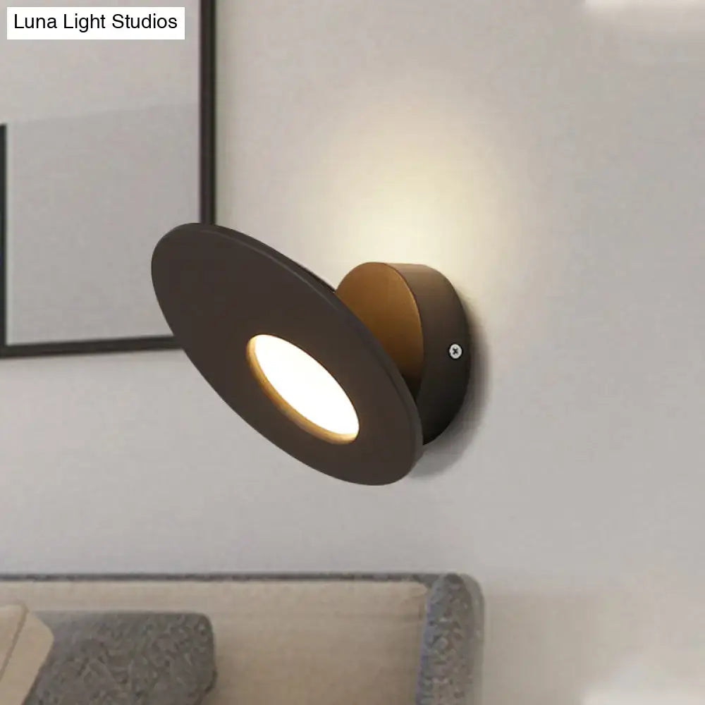 Modern matte black and brass wall lamp with round acrylic integrated led and minimalist circular design for bedroom use