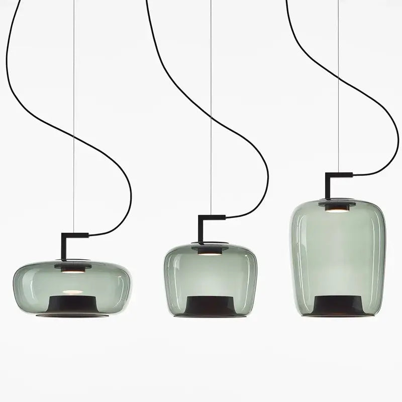 Three sleek translucent sage green brokis glass pendant lamps with black metal fixtures for dining room decorbites brokis glass