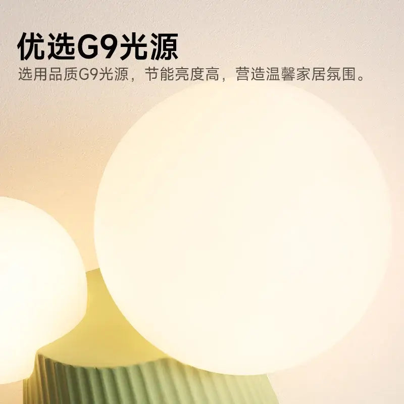 Warm softly glowing spherical wall lamp with smooth opaque white finish in modern sage green decorbites cactus resin design