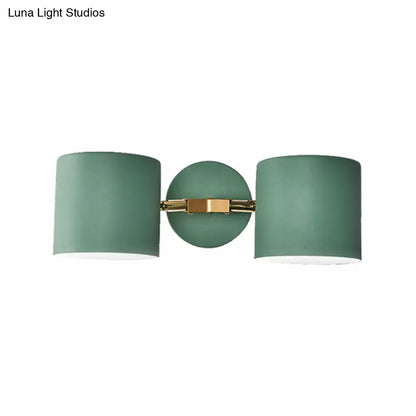 Modern sage green double shade wall sconce with matte cylindrical shades and brass bracket, 12 inches high for living room lighting