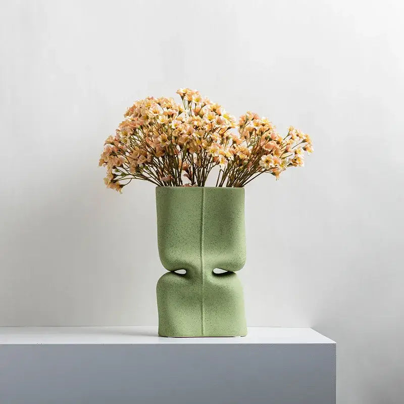 Modern sage green hollow ceramic vase with sculpted face design and cut-out eye sockets for living room decor