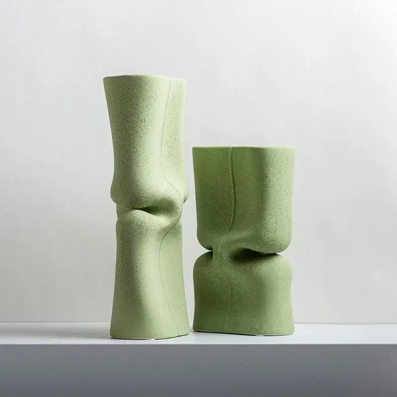 Two matte sage green hollow ceramic vases with organic sculpted forms for modern living room face decor