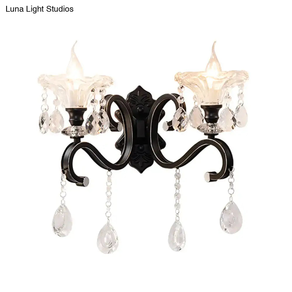 Black wrought iron wall lamp with curved arm, two candle-style glass shades, and dangling crystal teardrop pendants for e12 e14 bulbs