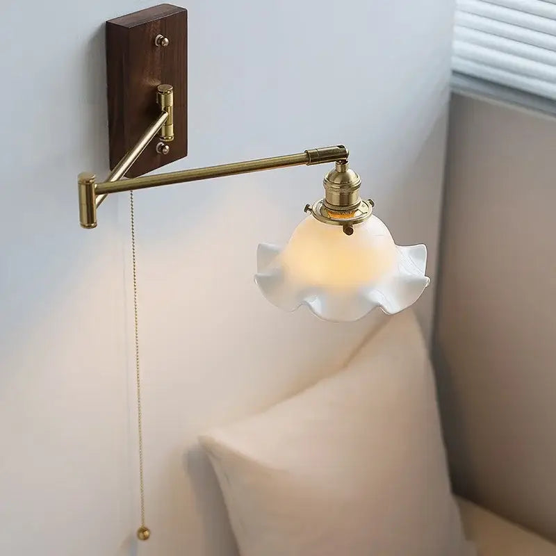 Modern scalloped glass and brass wall light with dark wood backplate and off-white ruffled shade for bedroom reading lamp