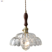 Modern scalloped glass flower led pendant light with clear glass, dark wood handle, and brass accents for dining room