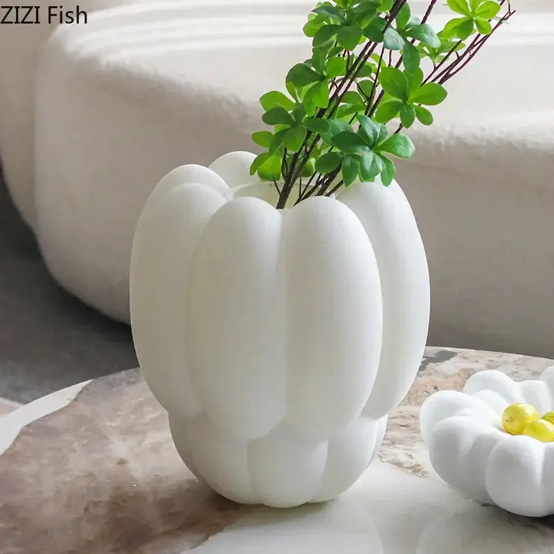 Modern scalloped white ceramic creative petal vase with segmented pumpkin design holding green artificial foliage