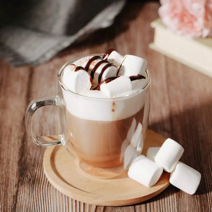 A clear double wall glass coffee cup filled with warm chocolate latte topped with whipped cream and marshmallows