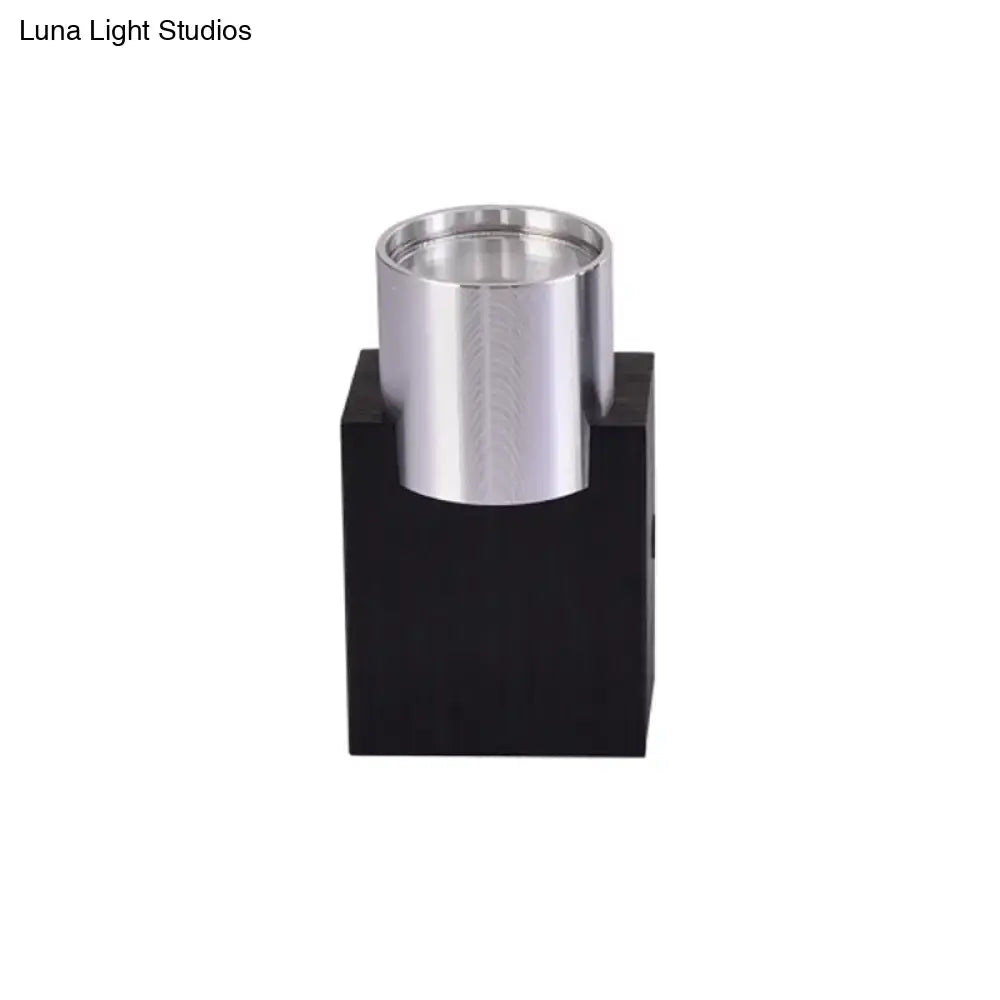 Modern silver aluminum cylindrical led wall light fixture mounted on a black base for bedroom accent lighting