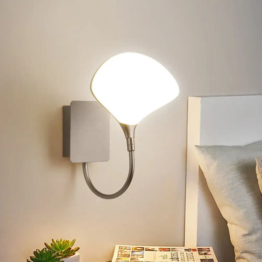 Modern silver arced arm wall lamp with a flexible arm and oval-shaped acrylic shade for bedroom lighting