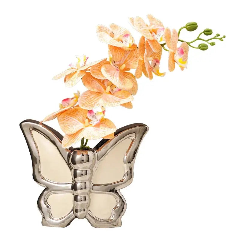 Shiny silver butterfly ceramic vase holding a delicate peach orchid arrangement for modern living room decor
