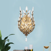 Gold-toned modern wall light with silver brass laurel design and crystal drop accents for bedroom lighting