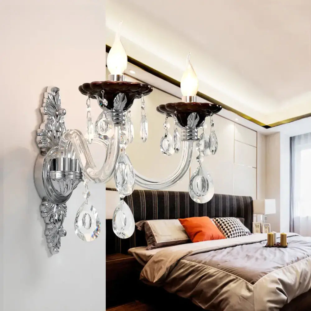 Modern silver candle wall mounted sconce with chrome ornate arms, dark brown ceramic bases, and clear glass teardrop crystals