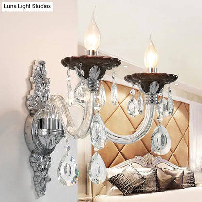 Modern silver candle wall mounted sconce with chrome finish, candle bulbs, crystal pendants, and ornate leafy detailing
