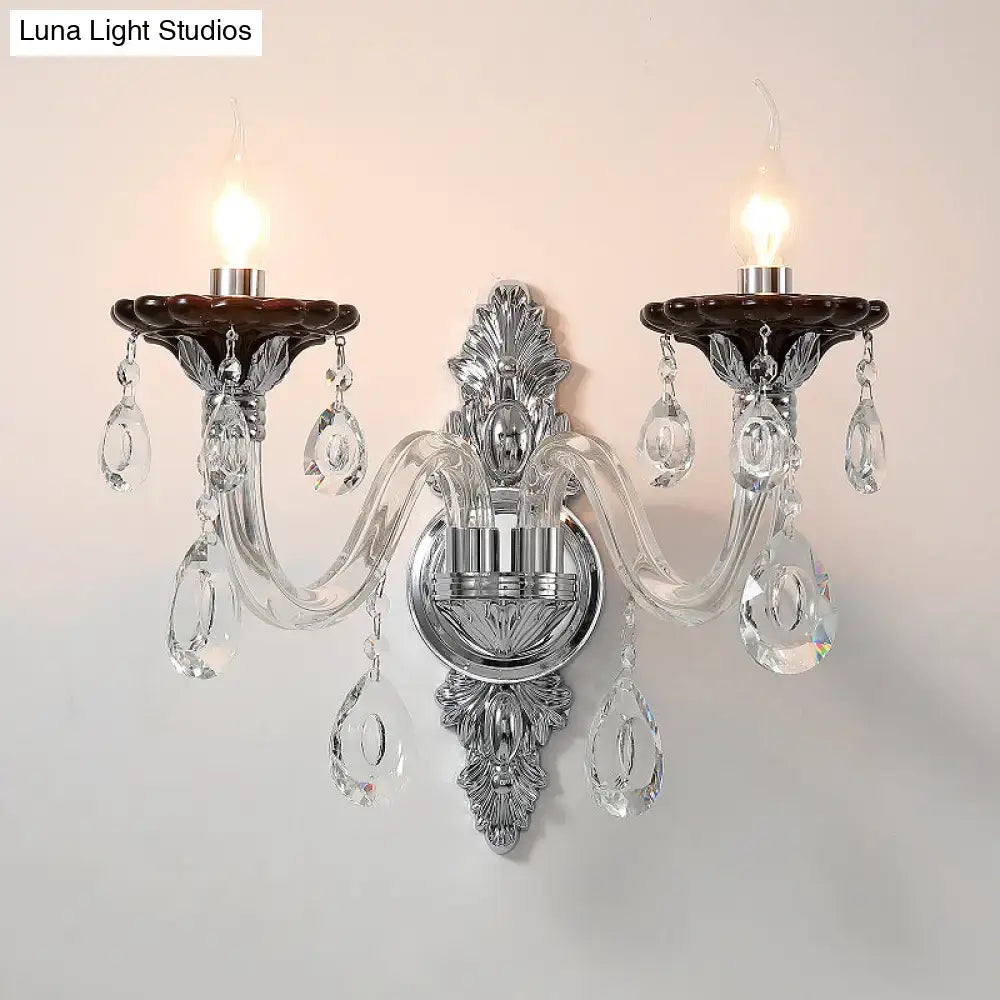 Modern silver candle wall mounted sconce with chrome finish, two dark brown ceramic holders, and crystal teardrop pendants