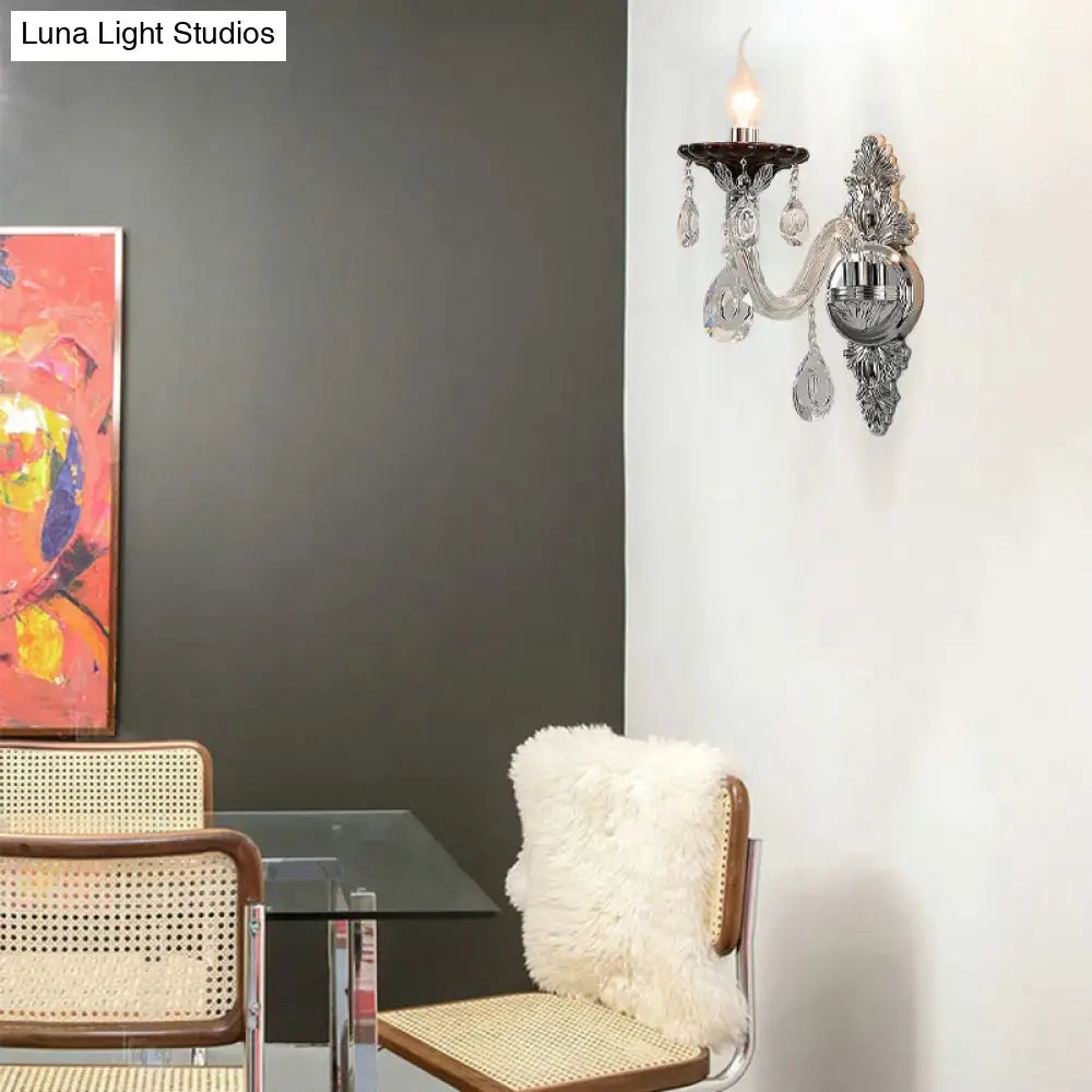 Ornate modern silver candle wall mounted sconce with crystal droplets and candle style bulb for bedroom lighting