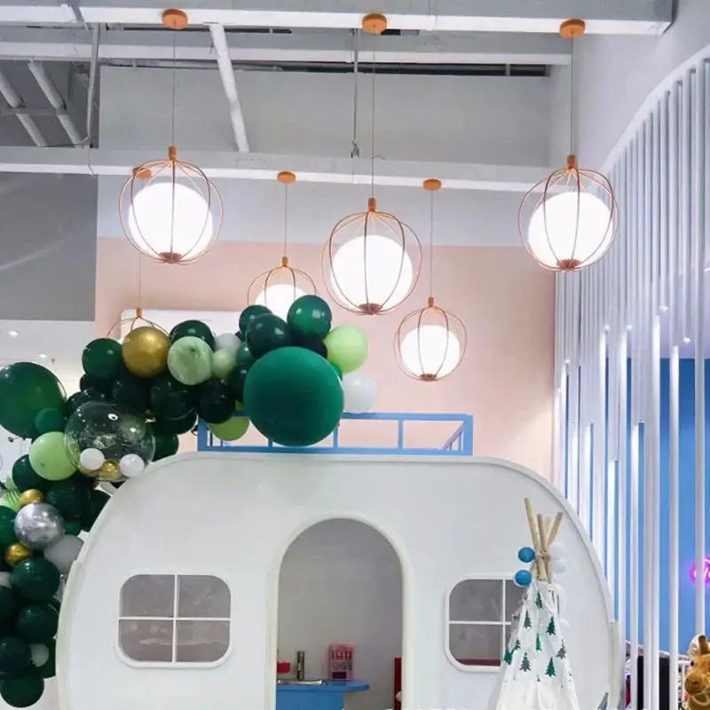 White camper-style playhouse with arched doorway and rectangular windows next to modern silver and copper glass ball pendant light