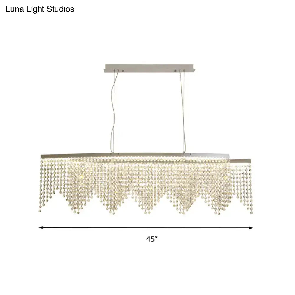 A modern silver crystal island pendant chandelier with a sleek metal frame and clear faceted beads for dining rooms