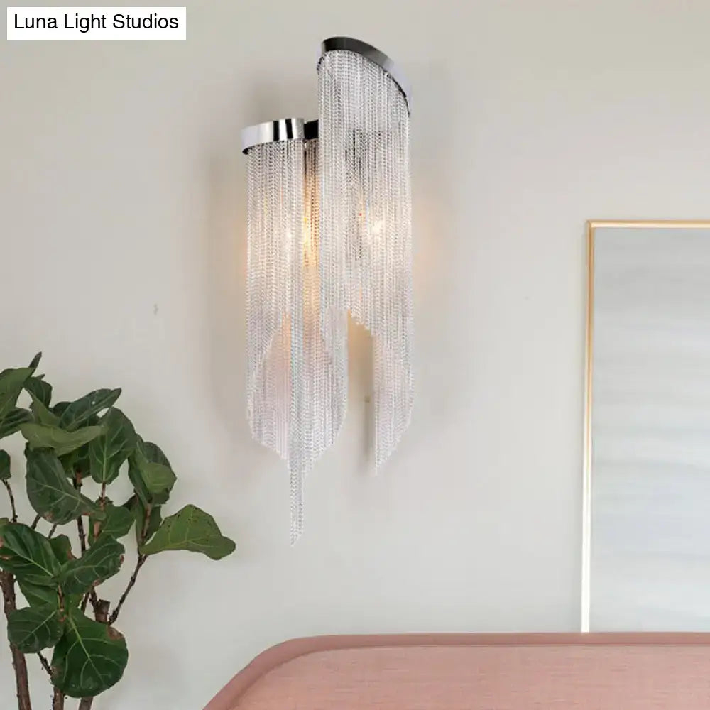 A modern wall light with light silver chrome finish and clear crystal tassel strands for living room illumination
