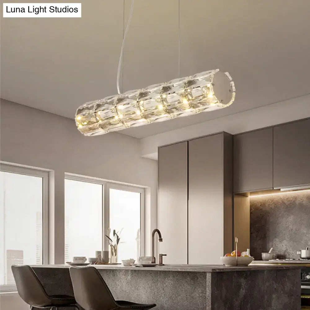 Modern silver crystal tube island light with cylindrical segmented faceted design refracting warm ambient lighting